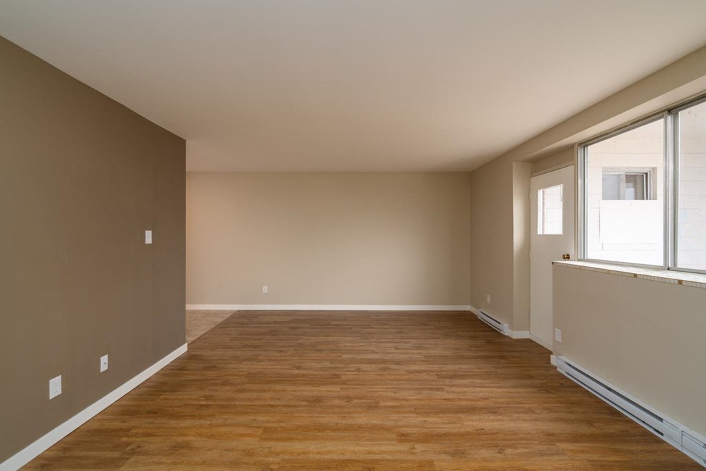 an empty room with a large window and wooden floors