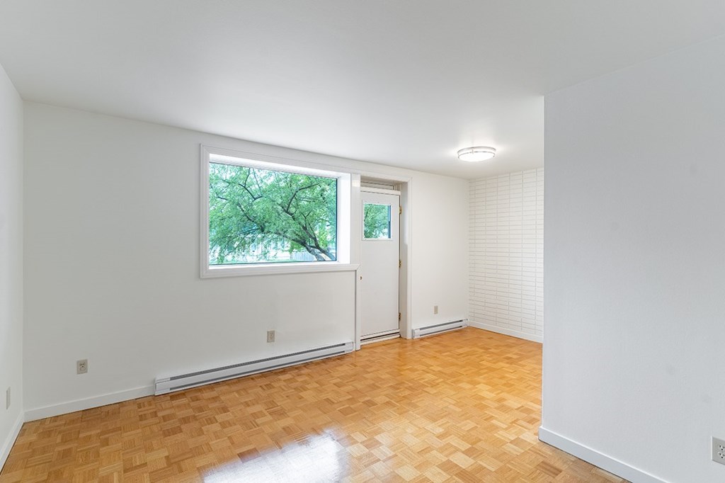 a bedroom with hardwood floors and a large window