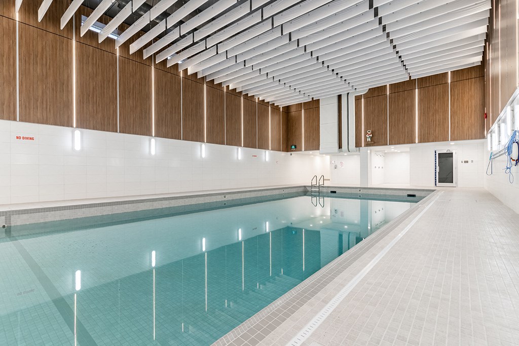 a swimming pool in a building with white walls and wooden ceilings