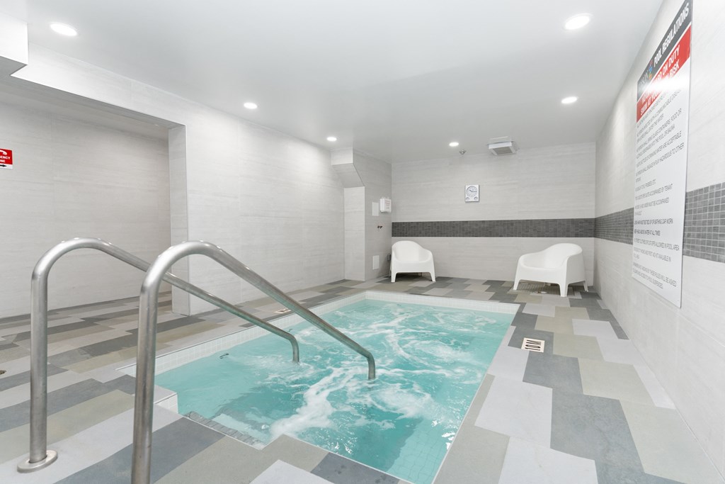 a indoor pool with a ladder in the middle of it and two chairs