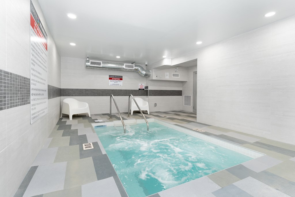a spa with a pool and chairs in a room with tile floors