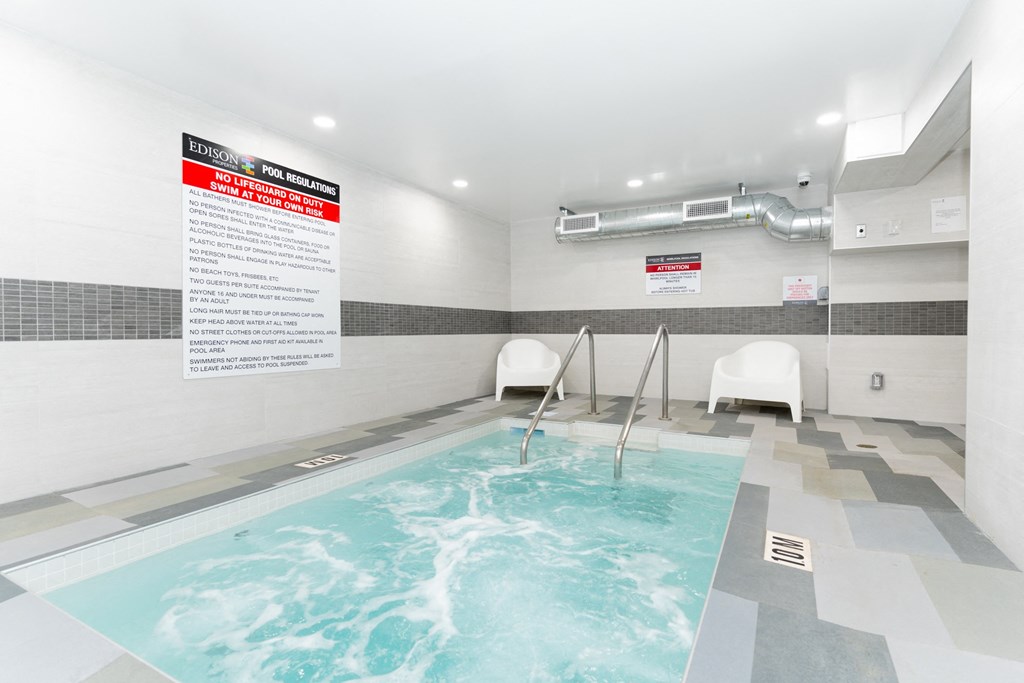 a spa with a pool and chairs in a room with a sign on the wall