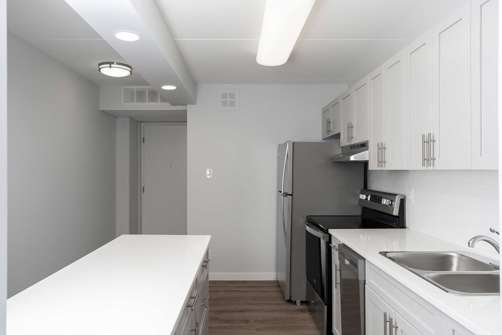 a kitchen with white countertops and a stainless steel refrigerator