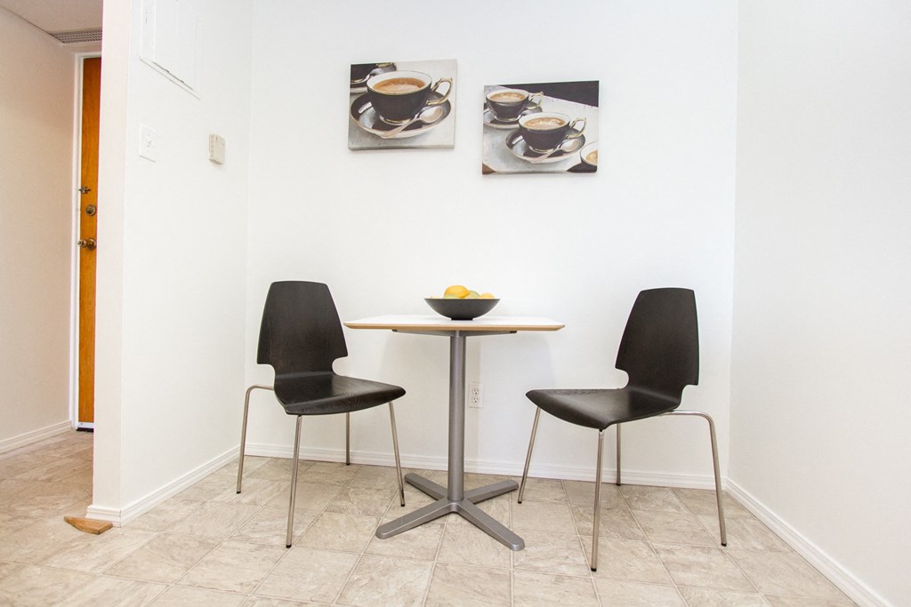 a small table with two black chairs in a white room