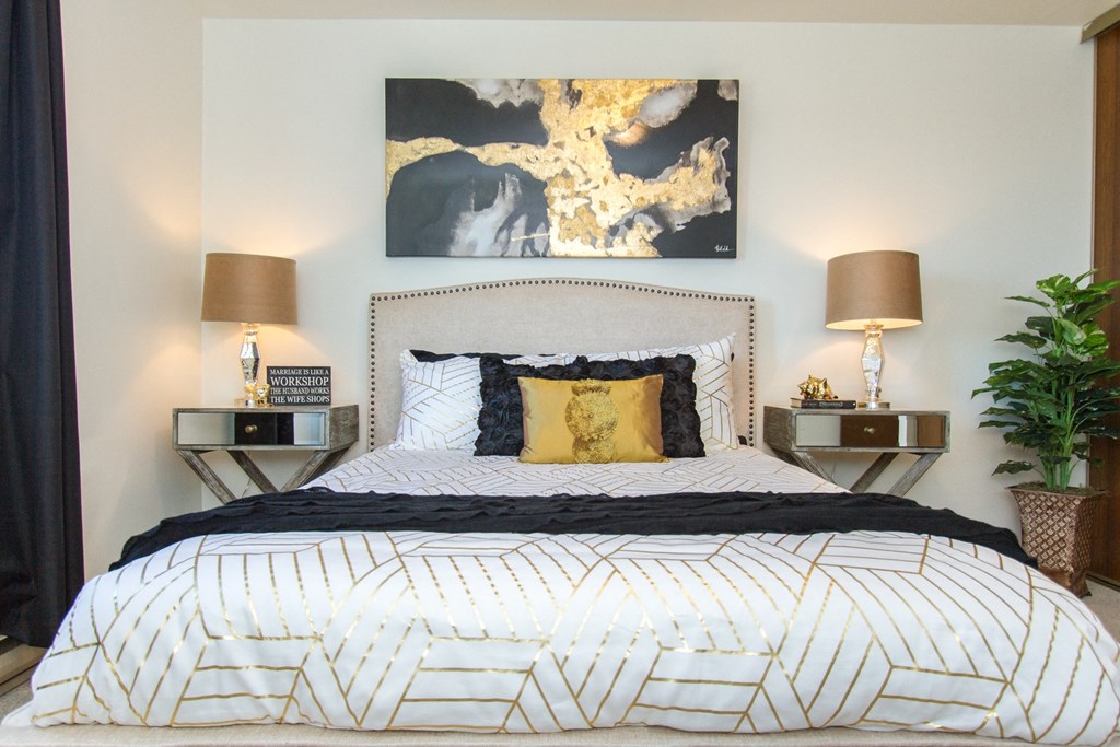 a bedroom with a bed and two nightstands with lamps on each side of the bed