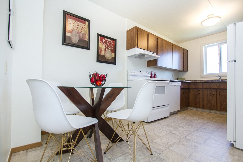 a kitchen and dining area with white chairs and wooden cabinets