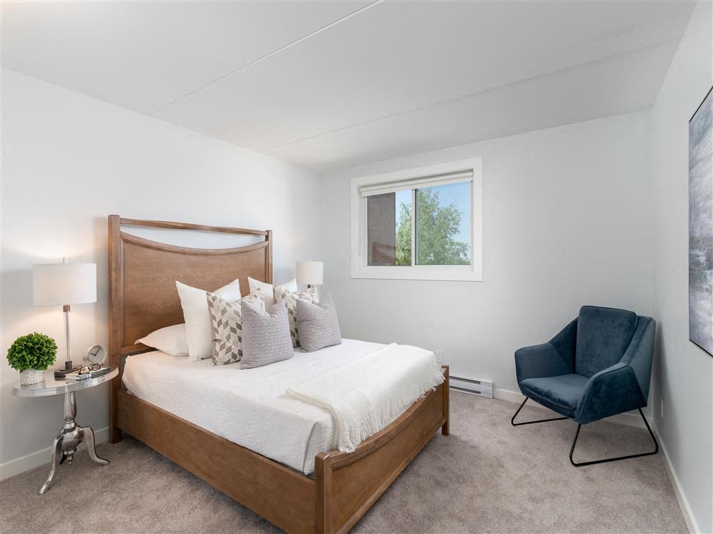 a bedroom with a bed and a chair and a window