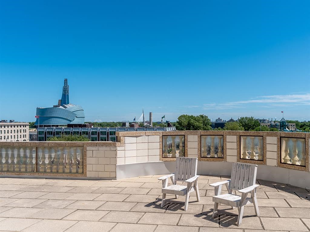 a roof terrace with two chairs and a view of the city