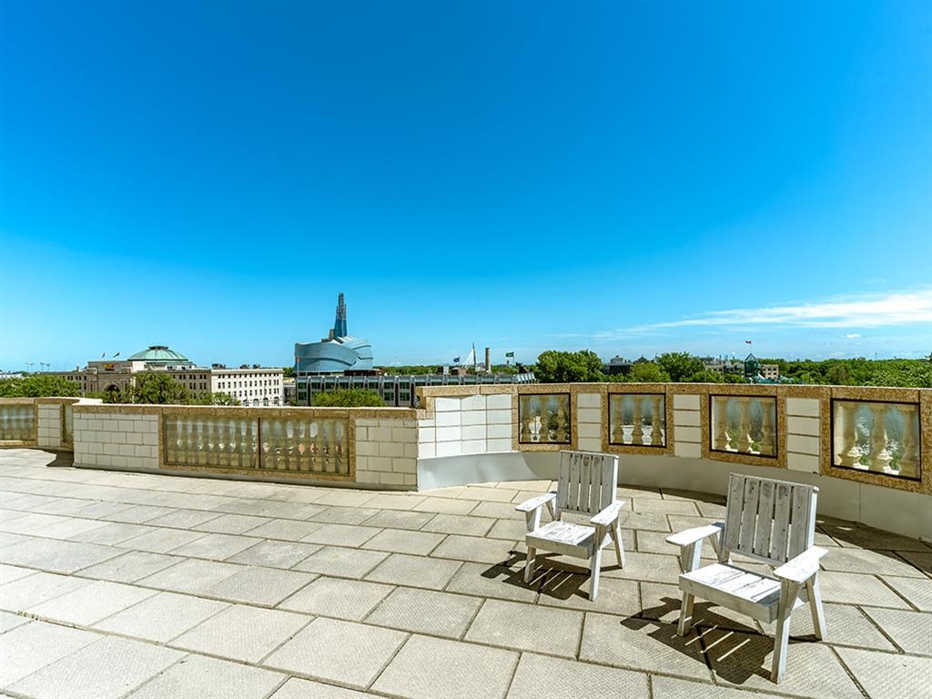 a roof terrace with two chairs and a view of the city