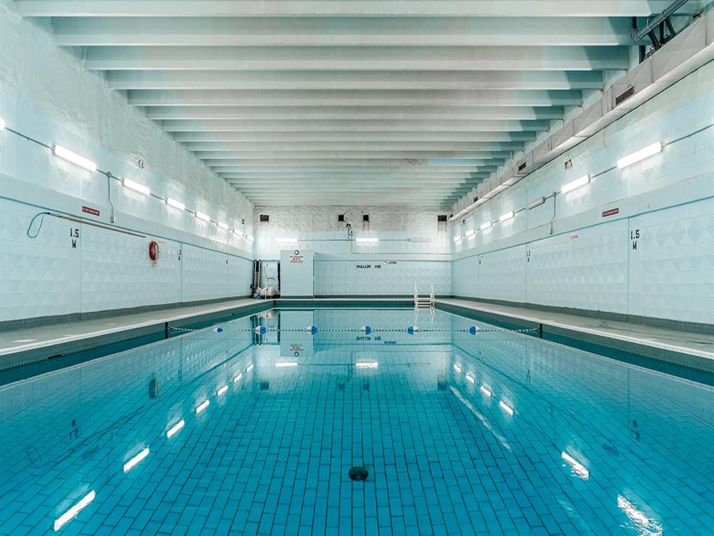 a large swimming pool in a building with white walls