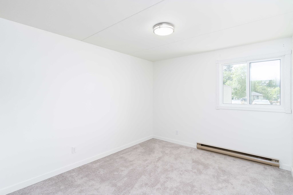a small room with white walls and a white window