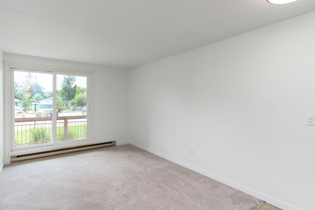 a bedroom with a large window and white walls