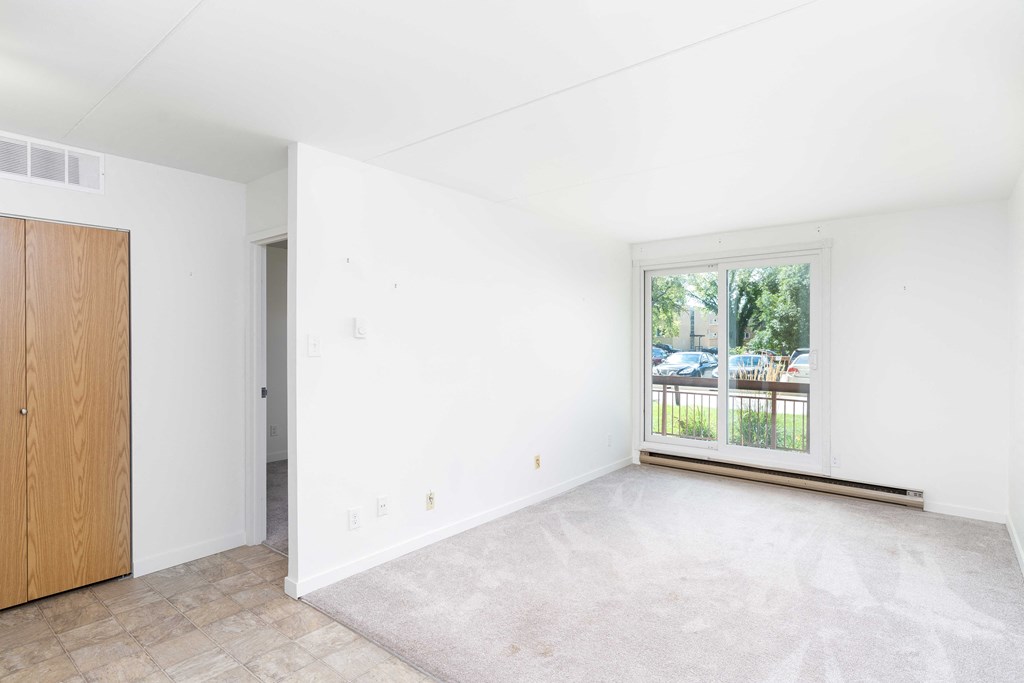 a bedroom with white walls and a large window