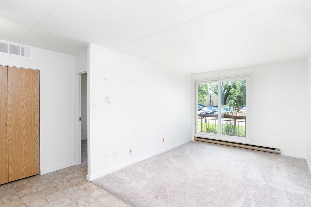 a bedroom with white walls and a large window