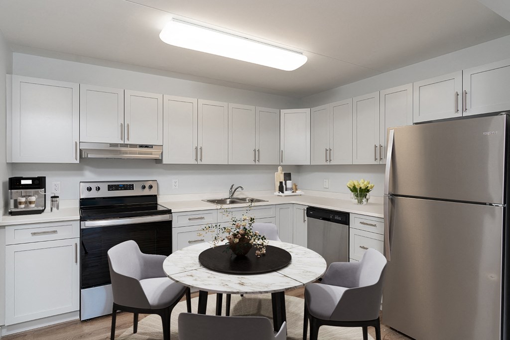 a kitchen with stainless steel appliances and a round table with white chairs