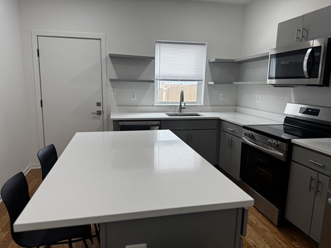 A white table is in the middle of a kitchen with a sink and a window.