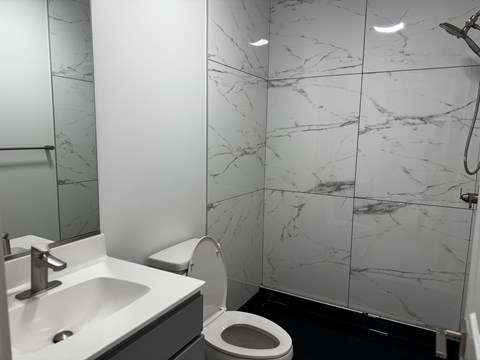 A bathroom with a sink, toilet, and marble tiles.