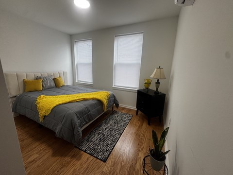 A bedroom with a bed, nightstand, and window.