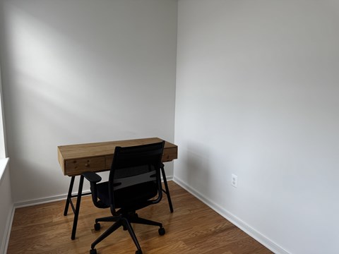 A black chair is in front of a wooden desk.