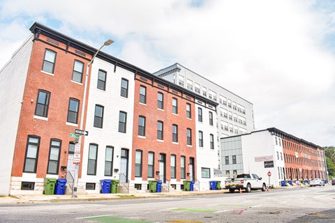 A row of red brick buildings with a white car parked in front of the white building.