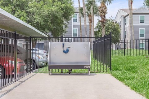 A gate with a blue logo stands in front of a building.