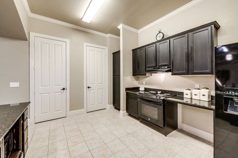 A kitchen with black cabinets and a white tile floor.