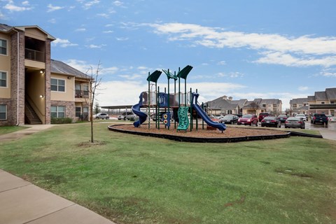 Playground with a slide and swings in a grassy area.