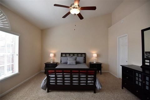 A bedroom with a bed, nightstands, and a ceiling fan.
