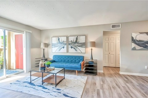 A living room with a blue couch and a painting on the wall.