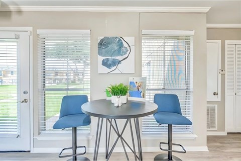 A dining room with a round table and blue chairs.
