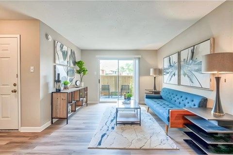 A living room with a blue couch and a rug.