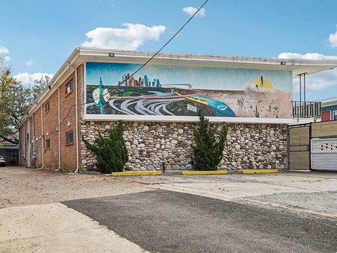 A mural on a building depicts a cityscape with a road winding through it.