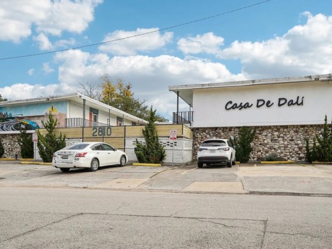 Two cars are parked in front of a building with the sign "Casa De Dali.".