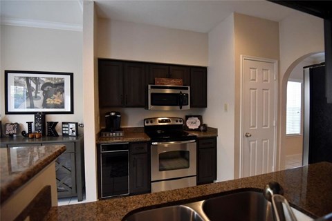 A kitchen with black cabinets and stainless steel appliances.