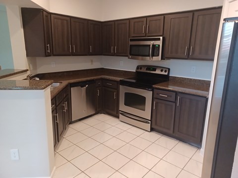 A kitchen with brown cabinets and a black stove top oven.