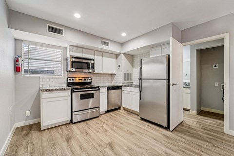 A kitchen with white cabinets and a stainless steel refrigerator.