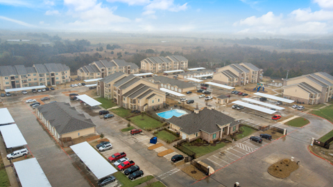 A large, modern housing complex with a swimming pool and parking area.