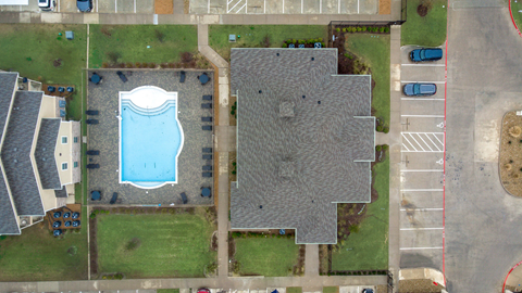 A swimming pool is surrounded by a grassy area and a building.