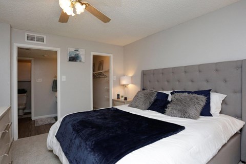 A bedroom with a large bed and a ceiling fan.