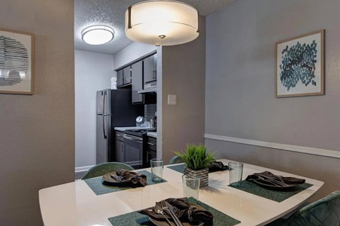 A modern dining area with a white table and green placemats.