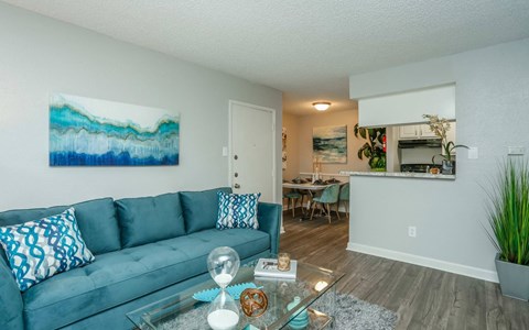 A living room with a blue couch and a painting on the wall.
