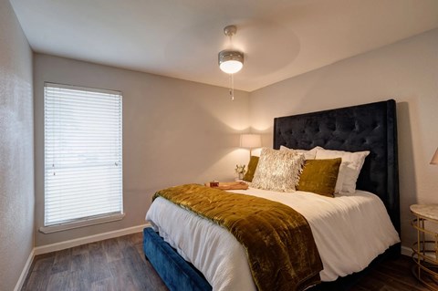 A bedroom with a large bed and a window with blinds.