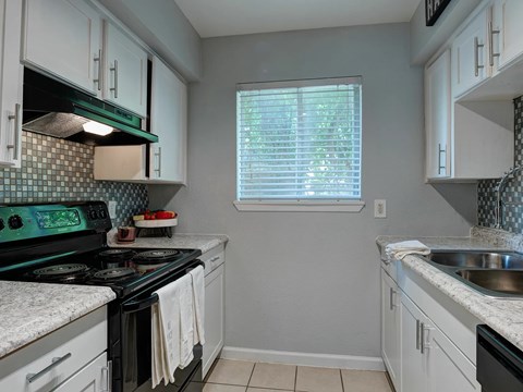 A kitchen with a black stove top oven and white cabinets.