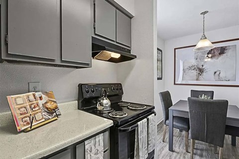 A kitchen with a stove, oven, and a dining table with chairs.