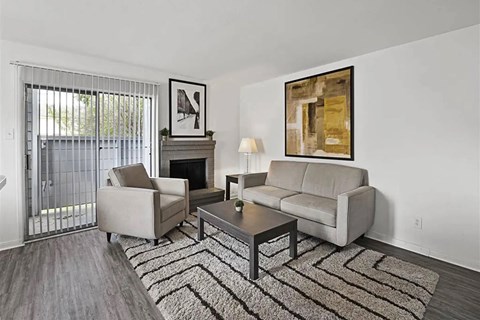 A living room with a grey couch, a coffee table, a fireplace, and a painting on the wall.