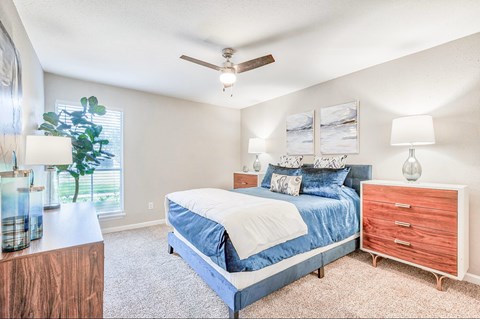 A bedroom with a bed, nightstand, and a ceiling fan.