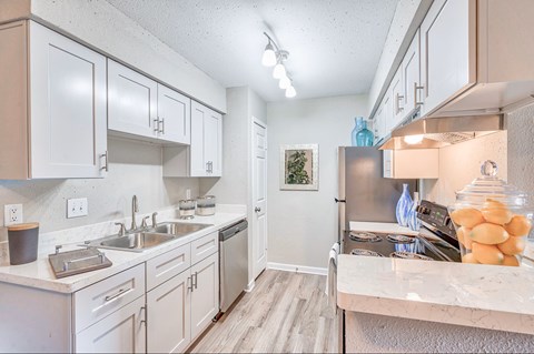 A kitchen with white cabinets and a marble countertop.