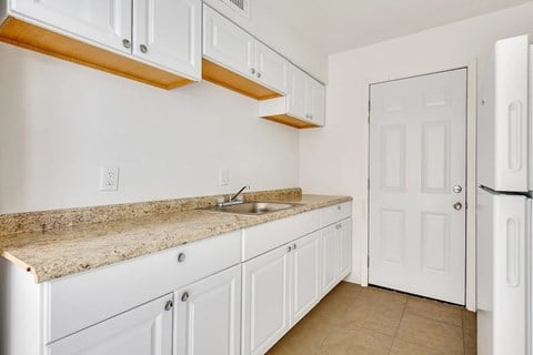 A kitchen with white cabinets and a granite countertop.