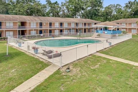 A swimming pool is surrounded by a fence in a grassy area.