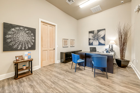 A room with a blue chair and a table with a laptop on it.